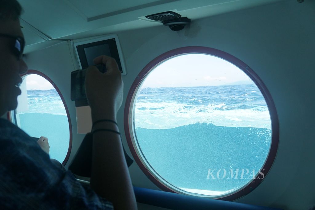 Penumpang memotret momen kapal selam wisata Golden Manta milik PT Bhineka Mancawisata mulai menyelam ke bawah laut dalam uji coba, Kamis (3/11/2022), di perairan Likupang, Minahasa Utara, Sulawesi Utara.