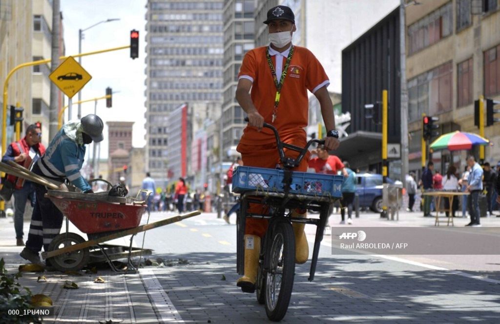 A worker rides a bike as he wears a face mask as a precautionary measure in the face of the global COVID-19 coronavirus pandemic, in Bogota on March 12, 2020. – Colombia declared on March 12, 2020 a “Health Emergency” due to the new coronavirus pandemic, a figure that allows it to take exceptional measures such as prohibiting the disembarkation of cruise ships and the holding of public events with more than 500 attendees. 
