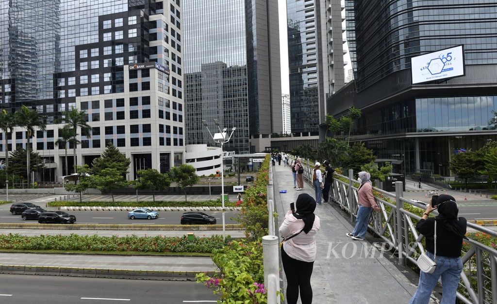 A number of young people enjoyed the city panorama while taking photos on the pedestrian bridge crossing Sudirman Street, Jakarta, on Sunday (27/2/2022).