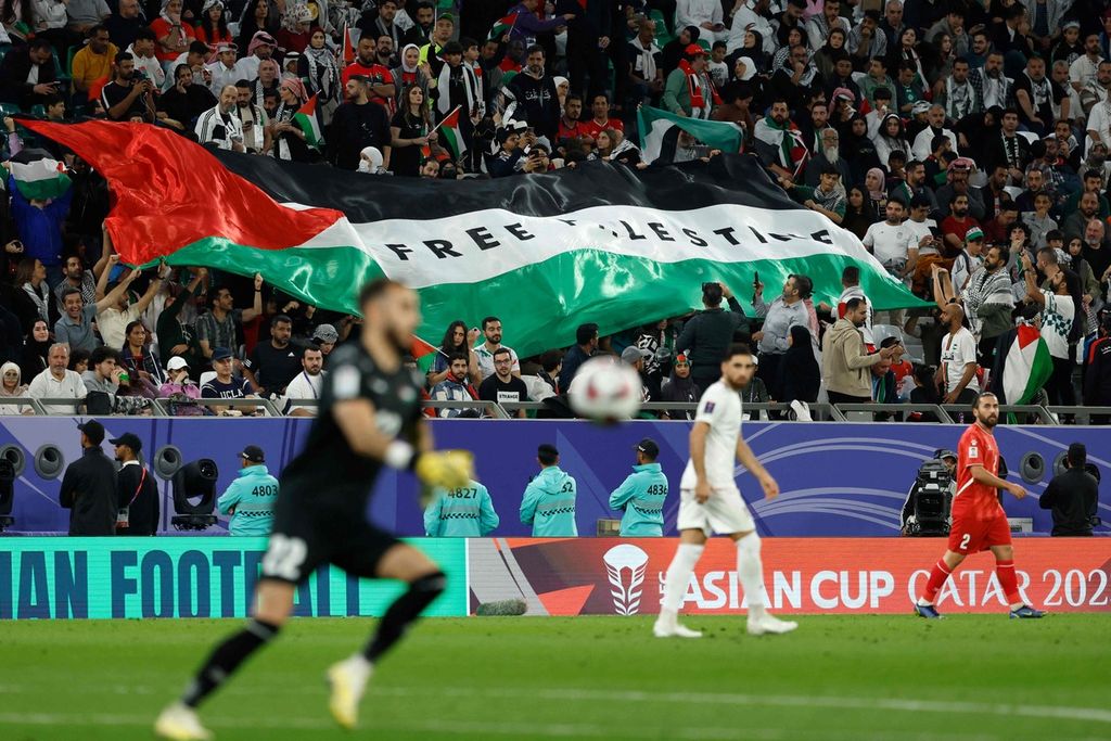 Suporter membentangkan bendera Palestina bertuliskan "Free Palestine" saat Palestina bertemu Iran pada laga penyisihan Grup C Piala Asia 2023 di Stadion Education City, Doha, Qatar, Senin (15/1/2024) dini hari WIB. Palestina kalah 1-4 pada laga ini.