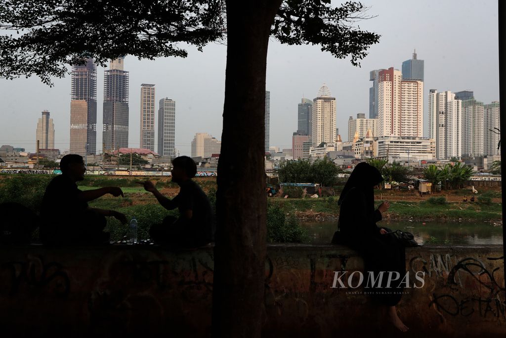 Warga mengobrol di kawasan Petamburan di samping Kanal Banjir Barat, Tanah Abang, Jakarta Pusat, Rabu (5/7/2023). 