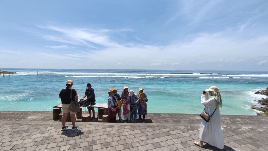 Wisatawan berfoto di kawasan Pantai Melasti, Desa Ungasan, Kuta Selatan, Kabupaten Badung, Bali (17/12/2021). Mulai 14 Maret 2022, wisatawan asing yang memenuhi syarat vaksin dan hasil PCR bisa masuk ke Bali tanpa karantina. 