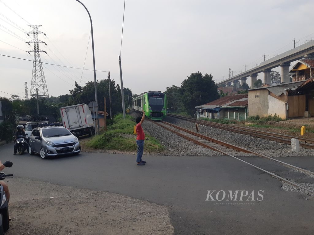 Pengendara mobil dan sepeda motor berhenti sejenak ketika kereta pengumpan untuk kereta cepat Whoosh melewati jalur pelintasan di Desa Cilame, Kabupaten Bandung Barat, Jumat (15/12/2023). 