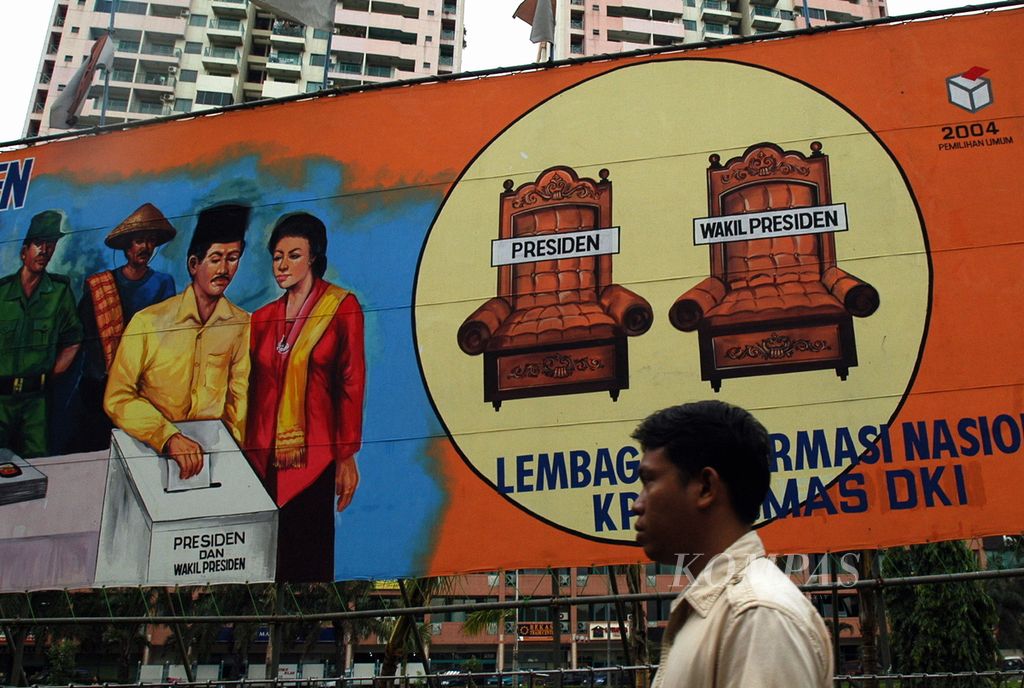 An employee passes in front of a billboard featuring the president and vice president chairs along with a number of citizens who cast their votes on Letjen Suprapto road, Central Jakarta, Thursday (10/6/2004). The direct presidential election, which will elect a presidential candidate for the first time, will be held in Indonesia on July 5th.