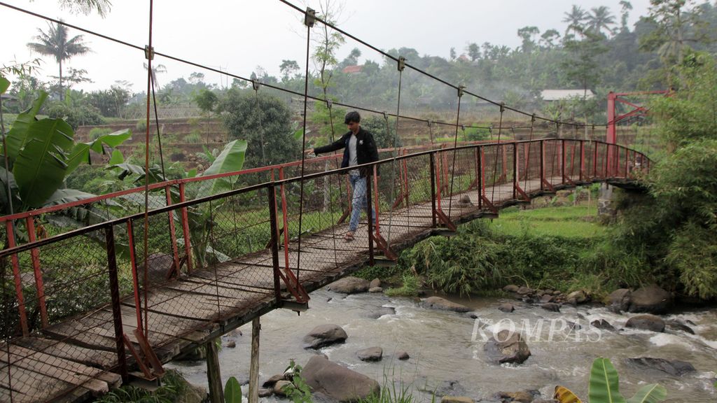 Warga berjalan kaki melintasi jembatan gantung Sungai Cihideung yang menjadi akses ke Kampung Cisasah dari Kampung Parung Jambu atau sebaliknya, Minggu (29/3/2020). Kedua kampung berada  di Desa Gunung Malang, Tenjolaya, Kabupaten Bogor, Jawa Barat. 