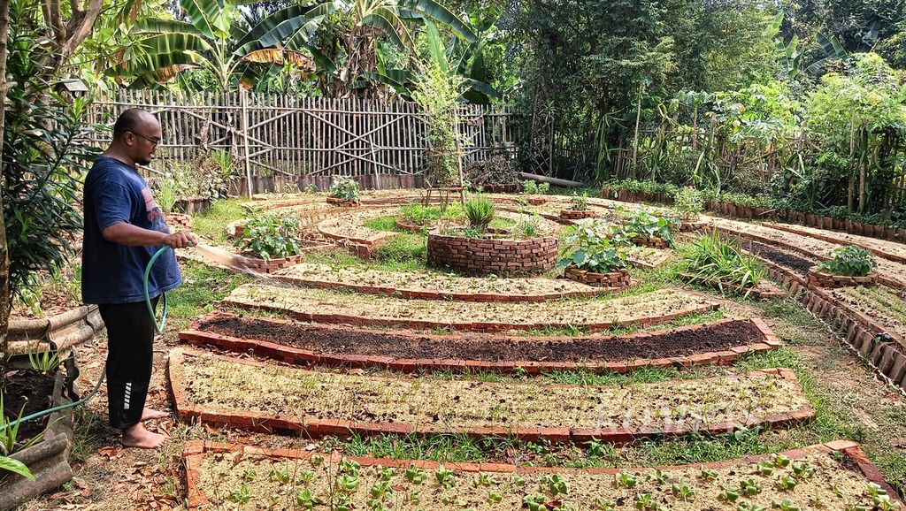 Stephanus Iqbal, suami Britania Sari, menyiram kebun di halaman belakang rumah mereka di Perumnas 2, Parung Panjang, Kabupaten Bogor, Jawa Barat, Sabtu (10/8/2024).