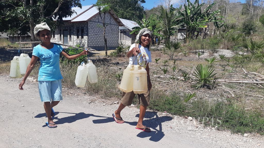 Warga berjalan kaki memikul air bersih yang diambil dari kali di Desa Oenoni, Kecamatan Amarasi Timur, Kabupaten Kupang, Nusa Tenggara Timur, Minggu (22/8/2021). 