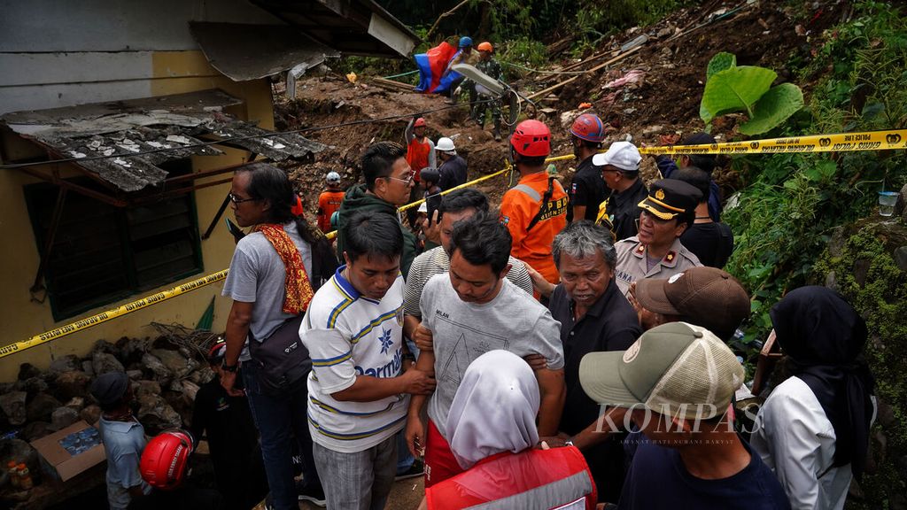 Misbah (36), korban selamat, melihat sejenak para petugas SAR gabungan melanjutkan pencarian korban yang masih tertimbun longsor di Kampung Sirnasari, Kelurahan Empang, Kota Bogor, Jawa Barat, Kamis (16/3/2023).