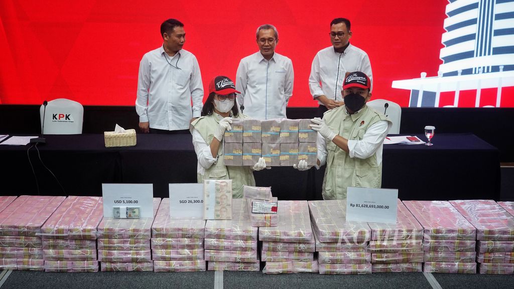 Petugas Komisi Pemberantasan Korupsi (KPK) mengangkat salah satu kantong plastik berisi uang saat digelar rilis barang bukti tindak pidana pencucian uang (TPPU) kasus yang terjadi di Papua di Gedung KPK, Jakarta, Senin (26/6/2023). 