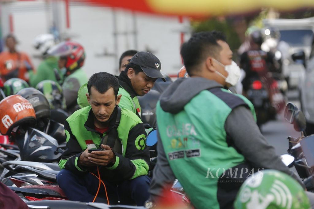 Pengojek daring mengecek pesanan melalui ponselnya di sekitar Stasiun Palmerah, Jakarta, Jumat (12/5/2023). BPJS Ketenagakerjaan mendorong pekerja informal, seperti pengojek daring, untuk menjadi peserta BPJS Ketenagakerjaan. 