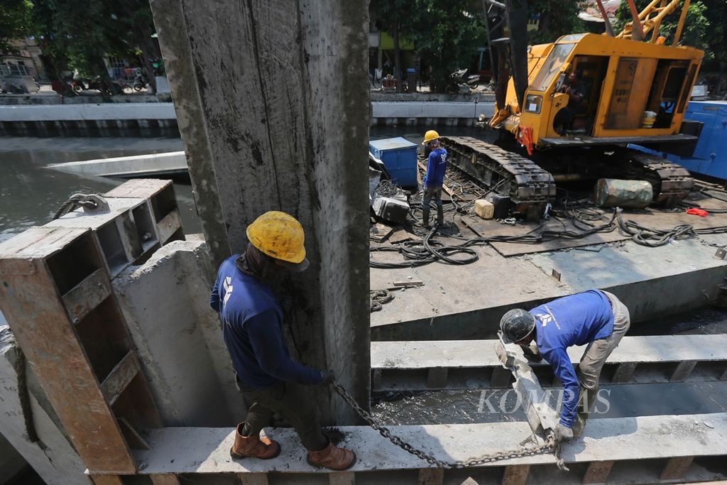Pekerja mengatur posisi turap sebelum dipasang di bantaran Kali Ciliwung di kawasan Kelurahan Ancol. Pademangan, Jakarta Utara, Selasa (19/11/2019). 