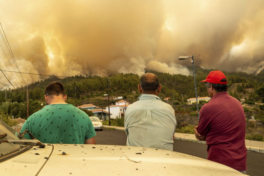 Tiga laki-laki memperhatikan dari jauh kebakaran hutan yang melanda La Palma, Kepulauan Canary, Spanyol, Sabtu (15/7/2023). Otoritas berwenang mengevakuasi sekitar 4000 warga dari dekat lokasi kebakaran. (Europa Press via AP)