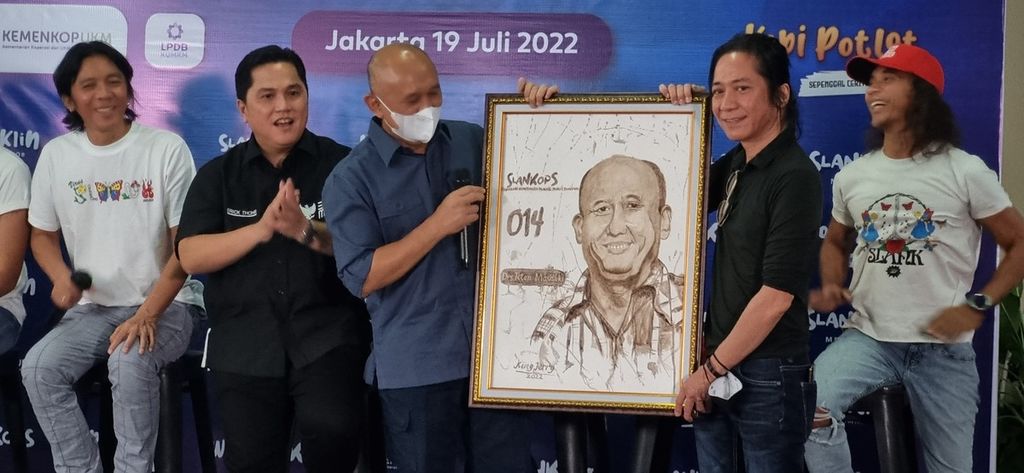 Menteri Koperasi dan Usaha Kecil Menengah Teten Masduki (ketiga dari kiri) menerima lukisan dari ampas kopi karya penggemar Slank dalam peluncuran pendirian koperasi yang diberi nama Slankops di markas Slank di Jalan Potlot III, Jakarta, Selasa (18/7/2022). 