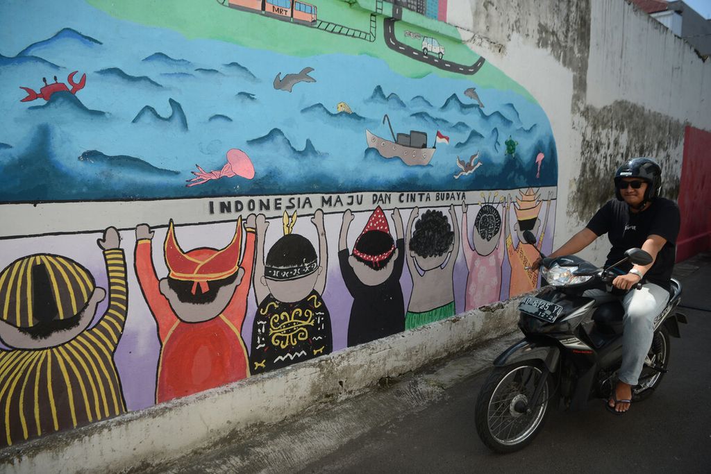 A motorcycle rider pass in front of the diversity mural on the walls of SMP Negeri 15 Surakarta, Laweyan, Solo, Central Java, Thursday (16/1/2020). Through the mural, it is hoped that the spirit of maintaining diversity will always flare up among students and the surrounding community.
