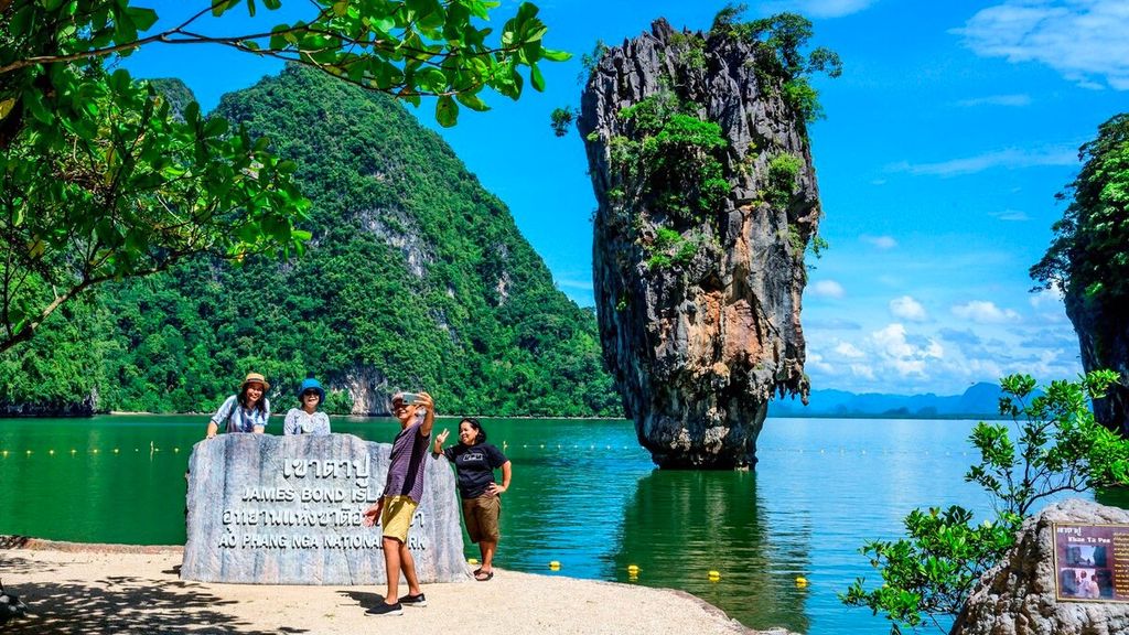 Turis domestik berfoto di depan Pulau James Bond di Teluk Phang Nga di timur laut Phuket, Thailand, Sabtu (30/10/2021). 