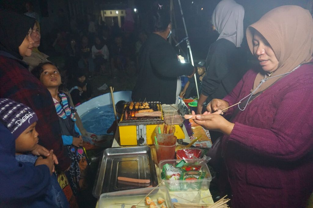 Pedagang sosis bakar melayani pembeli saat acara <i>layar tanjleb</i> dalam rangkaian Festival Film Purbalingga di Desa Toyareja, Kabupaten Purbalingga, Jawa Tengah, Sabtu (22/7/2023) malam.