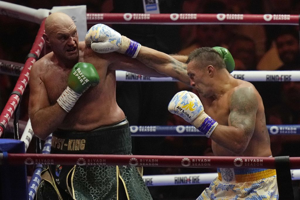 Petinju Inggris Tyson Fury (kiri) dan petinju Ukraina Oleksandr Usyk adu pukulan dalam pertandingan memperebutkan gelar juara dunia sejati kelas berat di Arab Saudi, Minggu (19/5/2024). Usyk menang angka atas Fury dan menjadi juara dunia tinju sejati kelas berat dalam 25 tahun terakhir.