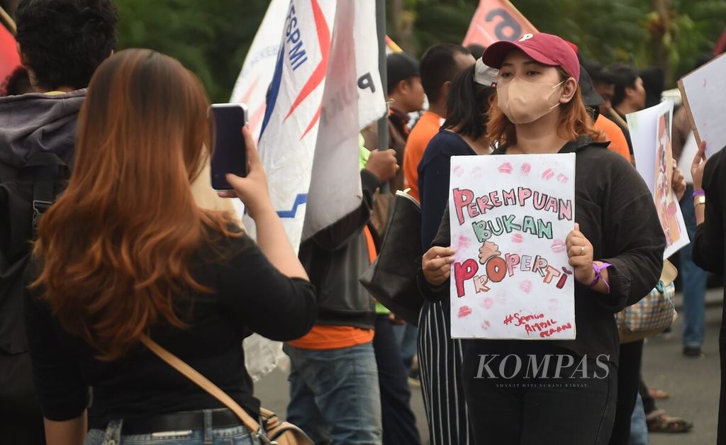 Seorang aktivis memotret rekannya yang tergabung dalam Aliansi Gerak (Gerakan Rakyat) saat berunjuk rasa memperingati Hari Perempuan Internasional di Jalan Gubernur Suryo, Surabaya, Jawa Timur, Rabu (8/3/2023). 