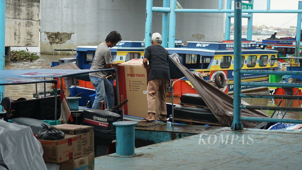 Dua orang sedang mengangkut barang elektronik masuk ke perahu cepat di Dermaga 16 Ilir, Palembang Sumatera Selatan, Selasa (20/12/2022). 