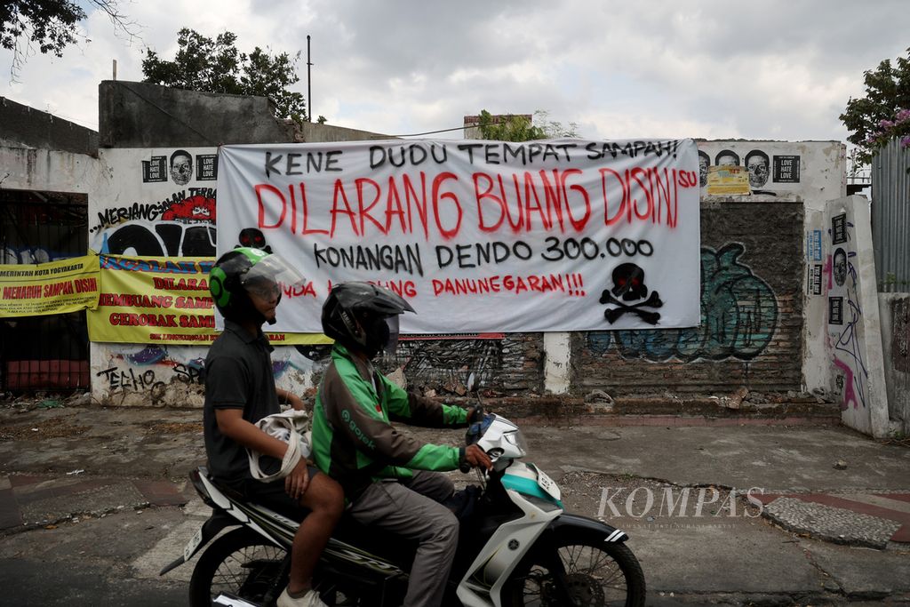 Pengguna jalan melintas di depan spanduk larangan membuang sampah di lokasi itu di kawasan Pojok Beteng Wetan, Yogyakarta, Kamis (14/9/2023). 