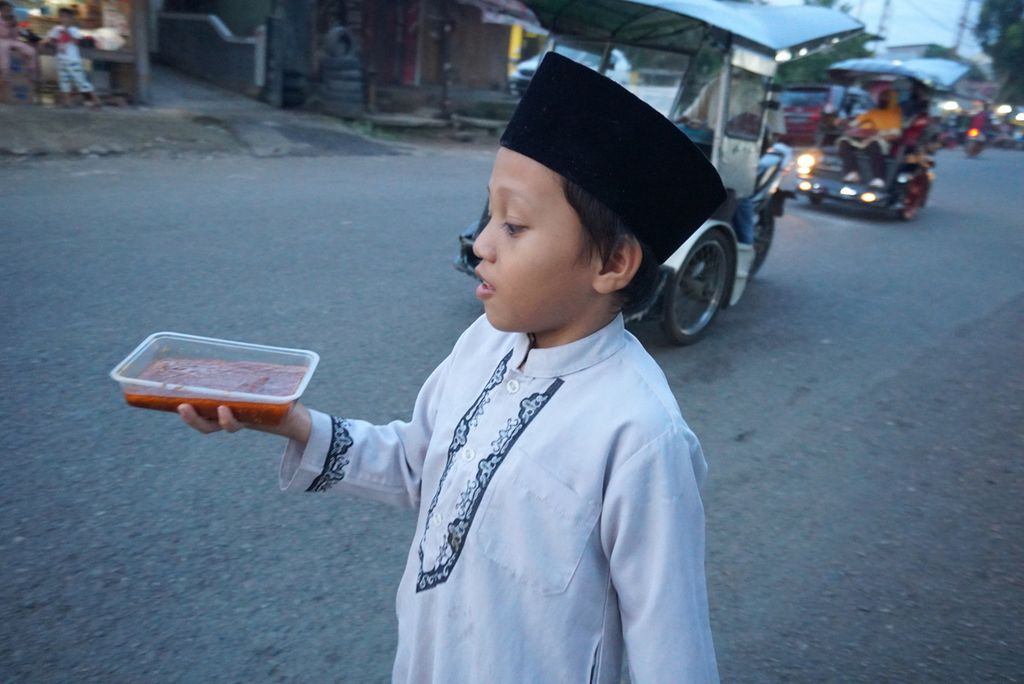 Seorang anak berjalan membawa makanan untuk berbuka puasa di Jalan Soeprapto, Gogagoman, Kotamobagu, Sulawesi Utara, Selasa (4/5/2021) sore.