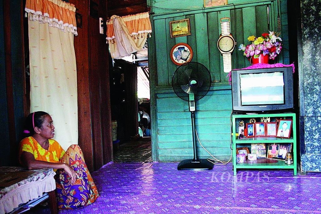 Hasidah (48), menonton siaran televisi di ruang tamu rumahnya di Desa Aji Kuning, Kecamatan Sebatik, Pulau Sebatik, Kabupaten Nunukan, Kalimantan Timur, Rabu (14/12). 