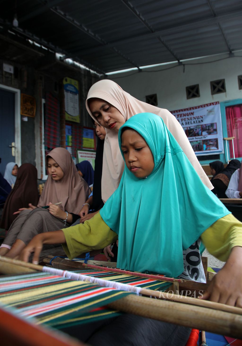 Seorang ibu memandu anak-anak belajar menenun di Sekolah Tenun Kelompok Nina Penenun di Desa Pringgasela Selatan, Kecamatan Pringgasela, Kabupaten Lombok Timur, Nusa Tenggara Barat, Minggu (17/12/2023). 