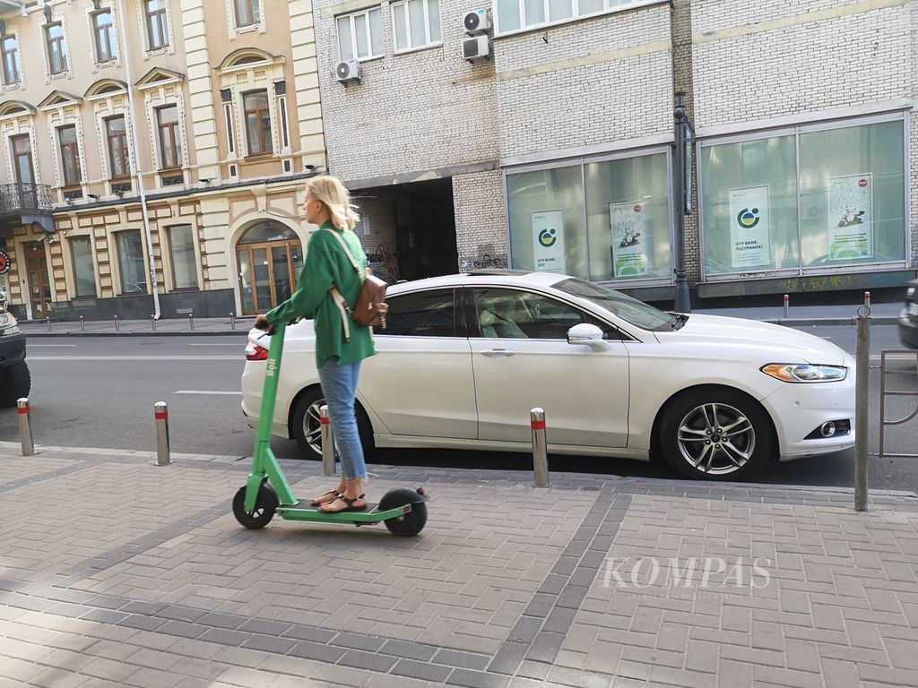 Warga menggunakan <i>otoped</i> Bolt di tepi jalan di sudut Kota Kyiv, Ukraina, Selasa (14/6/2022). Bolt adalah salah satu aplikasi untuk transportasi di kota Kyiv. Beragam aplikasi digital cukup membantu warga Kyiv di tengah banyak keterbatasan. 