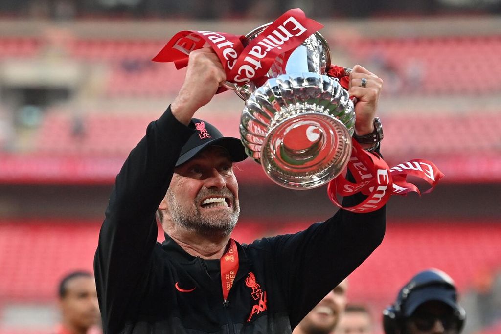 Manajer Liverpool Juergen Klopp mengacungkan trofi Piala FA seusai Liverpool mengalahkan Chelsea lewat adu penalti pada laga Piala FA di Stadion Wembley, London, Inggris, 14 Mei 2022.
