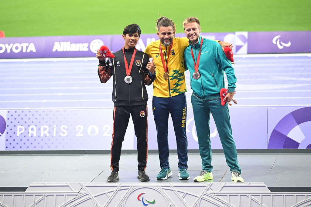 Peraih perak dari Indonesia, Saptoyogo Purnomo (kiri), Ricardo Gomes de Mendoca (emas/Brasil), dan Andrei Vdovin (perunggu) dari kontingen netral berpose menunjukkan medali yang diraih di nomor 100 meter Putra T37 di Stade de France, Saint Denis, Perancis, Jumat (30/8/2024).