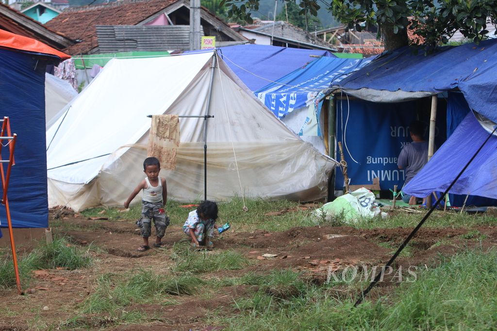 Dua anak bermain bersama di antara tenda darurat di Desa Cijedil, Kecamatan Cugenang, Kabupaten Cianjur, Jawa Barat, Sabtu (17/12/2022) siang.