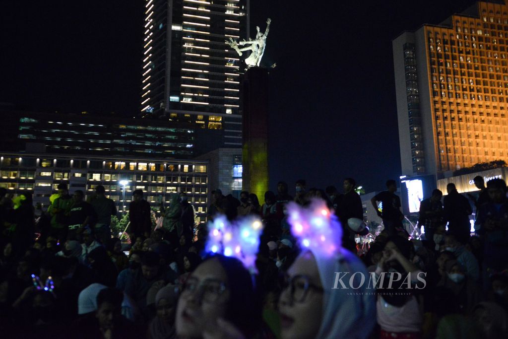 Sejumlah warga menggunakan bando yang dapat mengeluarkan cahaya di Bundaran HI, Jakarta Pusat, Sabtu (31/12/2022). Pemerintah Provinsi DKI Jakarta menutup sepanjang Jalan Sudirman sampai Jalan MH Thamrin untuk perayaan Tahun Baru 2023. 