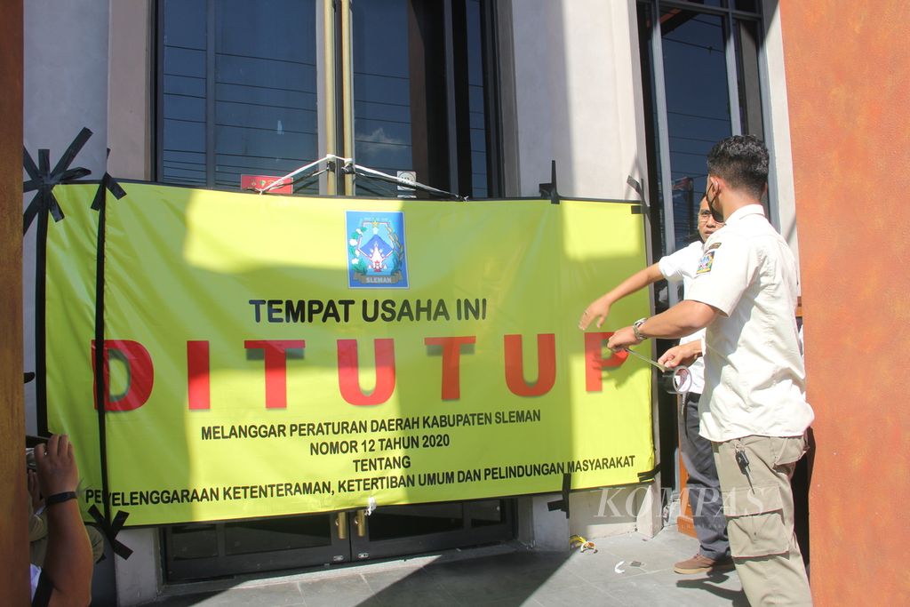 Petugas Satuan Polisi Pamong Praja memasang tanda penutupan bar dan restoran Holywings Jogja di Kabupaten Sleman, Daerah Istimewa Yogyakarta, Rabu (29/6/2022). 