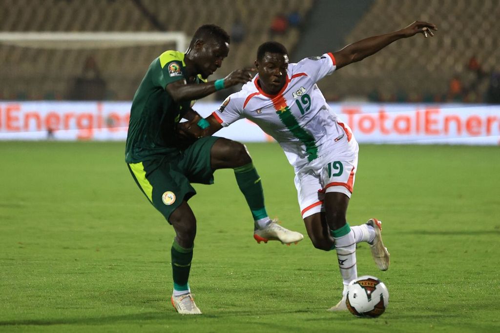 Pemain timnas Senegal, Idrissa Gana Gueye (kiri), berebut bola dengan pemain Burkina Faso, Boureima Hassane Bande, pada laga semifinal Piala Afrika di Stadion Ahmadou Ahidjo, Yaounde, Kamerun, Rabu (2/2/2022). Senegal memenangi laga itu dengan skor 3-1. 