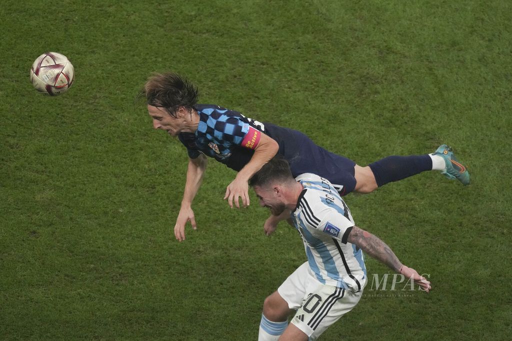 Gelandang Argentina, Alexis Mac Allister (bawah), berebut bola dengan bintang Kroasia, Luca Modric, di babak semifinal Piala Dunia 2022 di Stadion Lusail, Qatar, Rabu (14/12/2022) dini hari WIB. Argentina menang, 3-0, dan melaju ke final. 