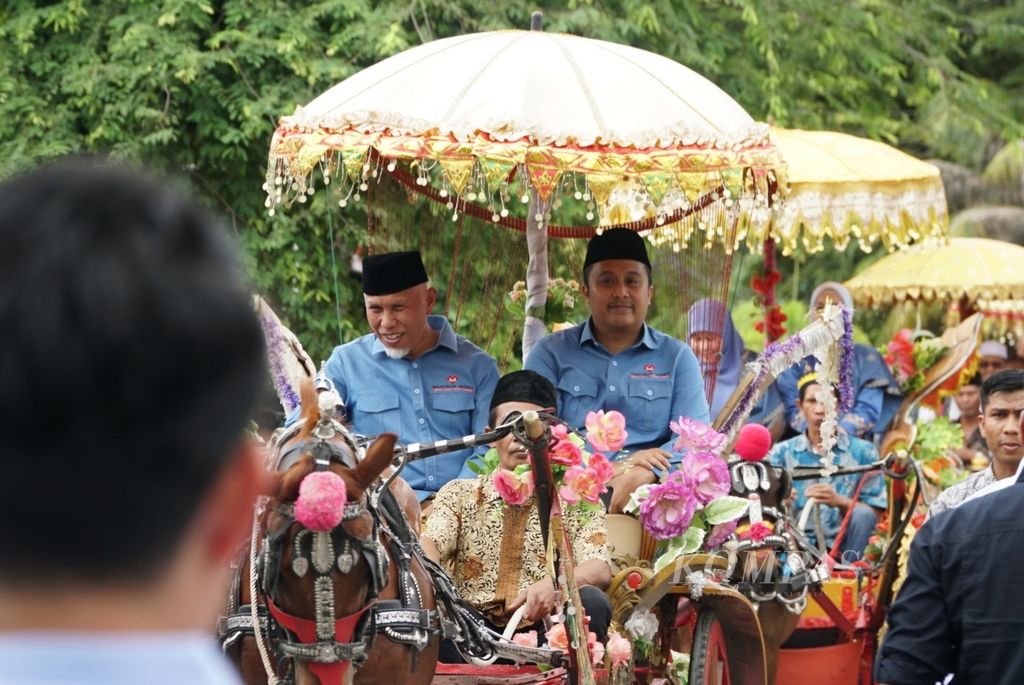 Bakal pasangan calon gubernur dan wakil gubernur Sumatera Barat, Mahyeldi (kiri) dan Vasco Ruseimy (kanan), menumpang arak-arakan bendi untuk mendaftar ke KPU Sumbar di Kota Padang, Selasa (27/8/2024). 