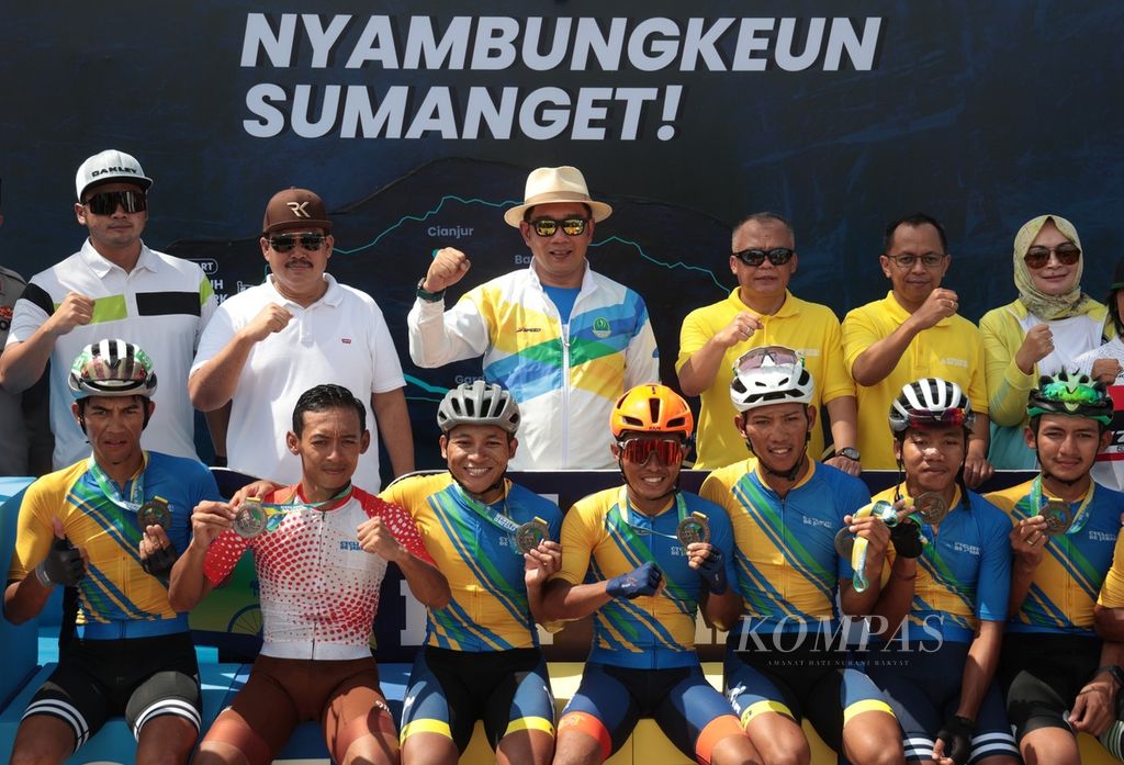 Gubernur Jawa Barat Ridwan Kamil (tengah) didampingi Bupati Pangandaran Jeje Wiradinata (dua dari kiri) berfoto bersama finisher yang berhasil menyelesaikan etape kedua Cycling de Jabar 2023 di Pangandaran, Jawa Barat, Minggu (9/7/2023).