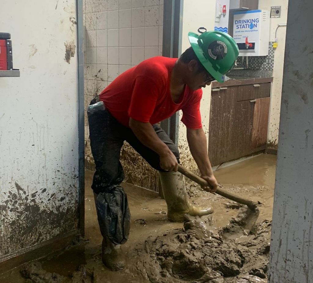 Salah seorang pekerja membersihkan lumpur di areal PT Freeport Indonesia di Distrik Tembagapura, Kabupaten Mimika, Papua Tengah, akibat diterjang banjir pada Sabtu (11/2/2023).