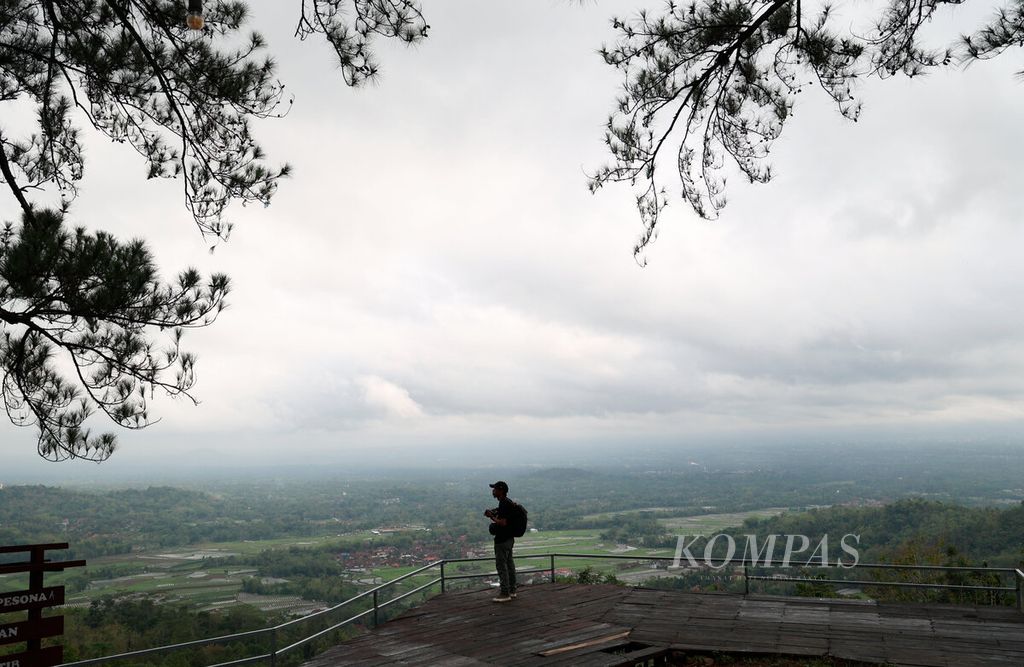 Tiyo, seorang fotografer, saat menikmati suguhan pemandangan kawasan perdesaan di sekitar Candi Borobudur dari puncak Pos Mati, Desa Giritengah, Kecamatan Borobudur, Kabupaten Magelang, Jawa Tengah, Minggu (4/12/2023).
