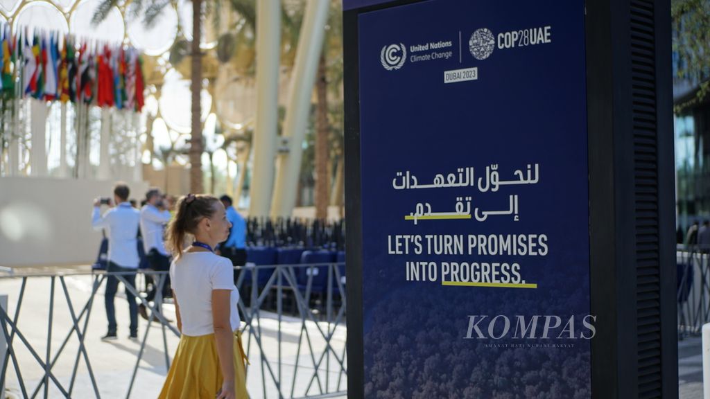 Seseorang melintasi papan salah satu slogan yang ada di area Konferensi Para Pihak tentang Perubahan Iklim Ke-28 atau COP28 di Dubai, Uni Emirat Arab, Rabu (30/11/2023). Perundingan dalam COP28 akan berlangsung selama dua minggu sejak 30 November-12 Desember 2023.