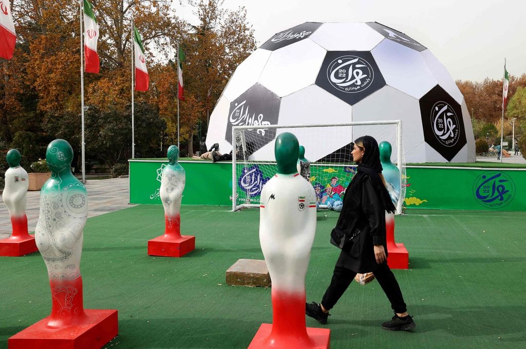 Seorang warga Teheran melintas di taman bertema sepak bola untuk menyambut Piala Dunia Qatar 2022 di depan Mellat Park, Teheran, Iran, Jumat (28/11/2022). 