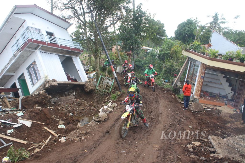 Para personel Tim Kopassus Trail Adventure melintasi reruntuhan bangunan di Desa Sarampad, Kecamatan Cugenang, Cianjur, Jawa Barat, Sabtu (26/11/2022).