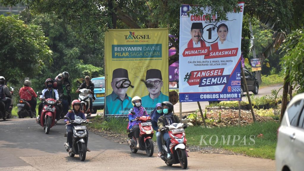 Warga melintasi poster para calon kepala daerah Pilkada Kota Tangerang Selatan, Banten, pada Pilkada Serentak 2020 di Kelurahan Sawah Baru, Ciputat, Tangerang Selatan, Sabtu (14/11/2020). 