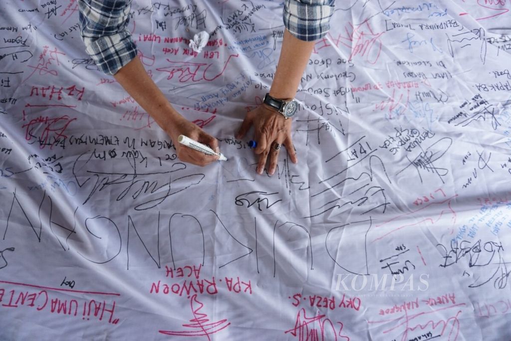 Warga membubuhkan tanda tangan di kain putih sebagai dukungan pengungkapan kasus kekerasan terhadap korban konflik Aceh, Selasa (14/8/2018).