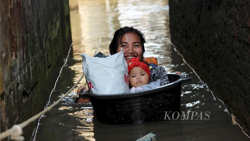 Warga menempatkan bayinya ke dalam ember untuk keluar dari permukiman yang dilanda banjir di Baleendah, Kabupaten Bandung, Jawa Barat, Rabu (10/4/2019). Lebih dari 37.000 jiwa terdampak akibat banjir luapan Sungai Citarum tersebut.