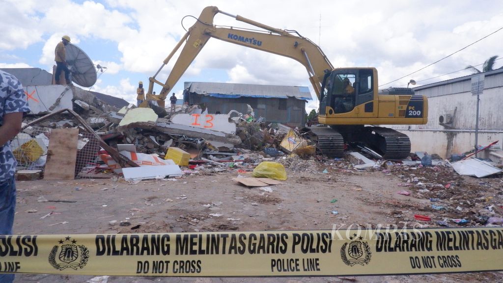 Alat berat jenis ekskavator kembali dikerahkan saat tim laboratorium forensik Kepolisian Daerah Jawa Timur memeriksa lokasi bangunan ruko Alfamart yang ambruk di Kecamatan Gambut, Kabupaten Banjar, Kalimantan Selatan, Rabu (20/4/2022). 