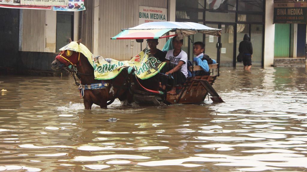 Warga menggunakan dokar untuk melintasi banjir di Jalan Anggadireja, Baleendah, Kabupaten Bandung, Jawa Barat, Rabu (1/3). Hujan deras dalam sepekan terakhir membuat kawasan Bandung selatan dilanda banjir hingga setinggi 1,5 meter dan membuat lebih dari 500 orang mengungsi.