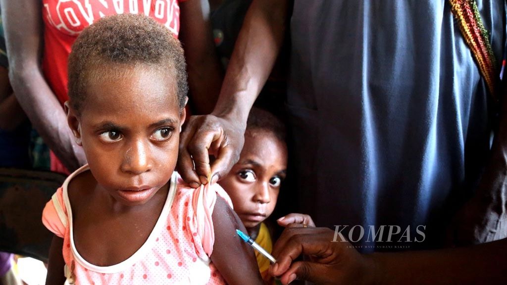 Petugas kesehatan dari Tim Khusus Penanggulangan KLB Campak dan Gizi Buruk memberikan vaksin campak bagi anak-anak di Kampung Atat, Distrik Pulau Tiga, Kabupaten Asmat, Papua, Sabtu (13/1/2018).