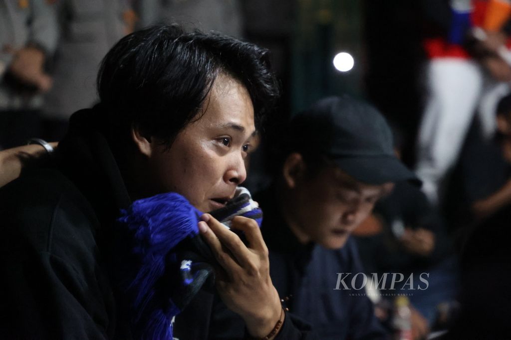 Seorang suporter kesebelasan Arema Malang menangis setelah berbicara dalam acara doa bersama untuk mendoakan para korban tragedi Stadion Kanjuruhan di Stadion Mandala Krida, Yogyakarta, Selasa (4/10/2022) malam. 