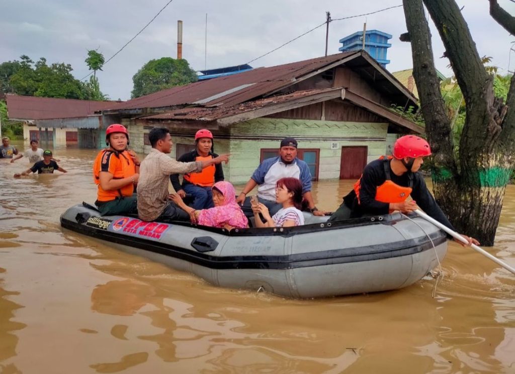 Petugas Badan Penanggulangan Bencana Daerah Kota Medan mengevakuasi warga dari rumahnya yang terendam banjir di sekitar Sungai Deli, di Medan, Senin (28/2/2022). 